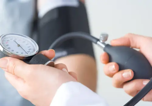Eine Nahaufnahme eines medizinischen Fachpersonals, das den Blutdruck eines Patienten mit einem Blutdruckmessgerät misst, um zu veranschaulichen, wie genaue Messwerte dabei helfen können, den Erfolg von Weiterbildungen im medizinischen Bereich zu messen.