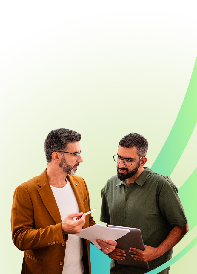 Zwei Männer diskutieren Dokumente; einer hält Klemmbrett und Stift, der andere ein Tablet. Der helle Hintergrund mit grünen, geschwungenen Linien lässt auf eine professionelle Umgebung schließen, möglicherweise im Zusammenhang mit einem Seminar zum Konfliktmanagement.